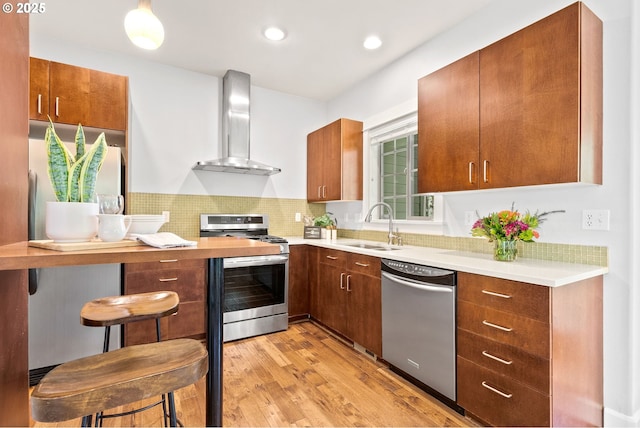 12842 Boones Ferry Rd, Lake Oswego, OR 97035 - kitchen featuring appliances with stainless steel finishes, wall chimney exhaust hood, light countertops, light wood-type flooring, and recessed lighting