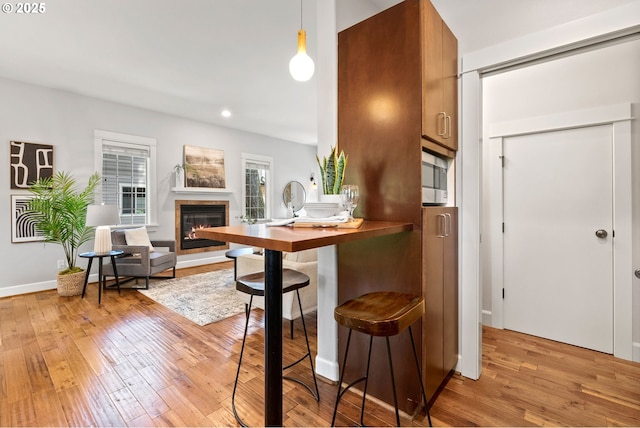 12842 Boones Ferry Rd, Lake Oswego, OR 97035 - kitchen with light wood-style flooring, a glass covered fireplace, recessed lighting, pendant lighting, and brown cabinetry