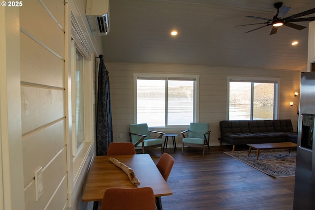 living area with a wealth of natural light, a wall mounted air conditioner, vaulted ceiling, and wood finished floors