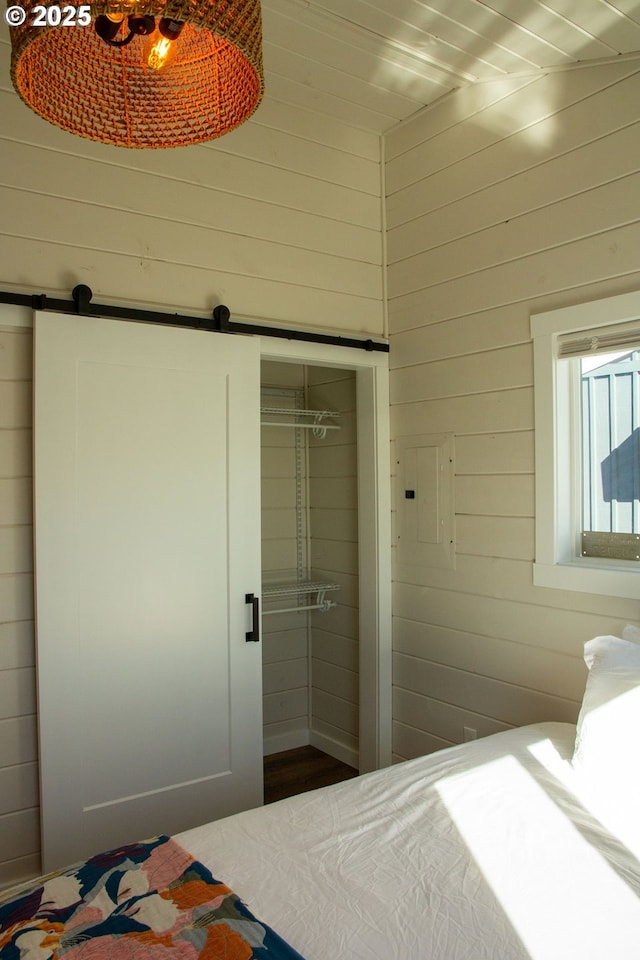 unfurnished bedroom featuring a barn door and wooden walls