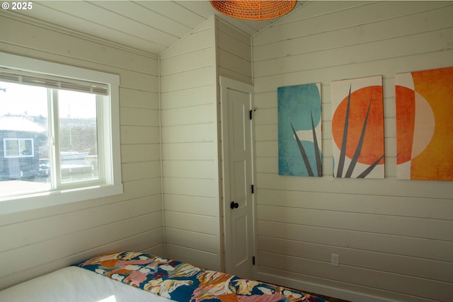 bedroom with lofted ceiling and wood walls