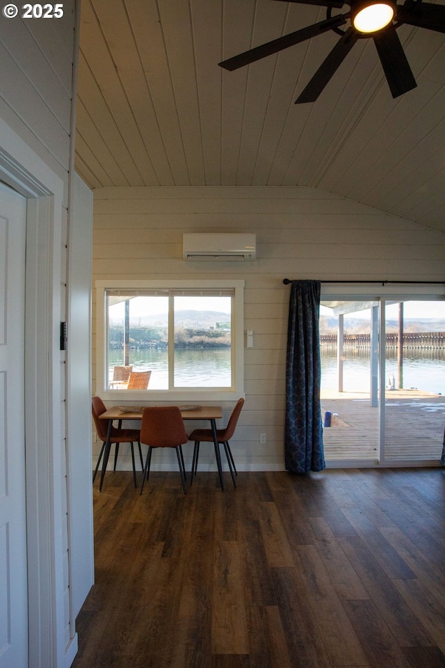 dining space with a water view, dark wood finished floors, an AC wall unit, and lofted ceiling