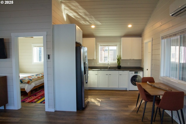 kitchen featuring washer / dryer, stainless steel fridge, plenty of natural light, and an AC wall unit