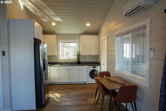 kitchen featuring a sink, a wall mounted AC, stainless steel fridge with ice dispenser, washer / clothes dryer, and dark countertops