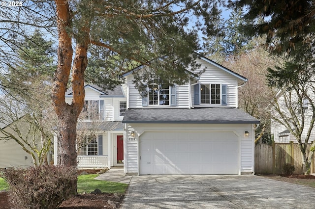 traditional-style house with a garage, a shingled roof, driveway, and fence