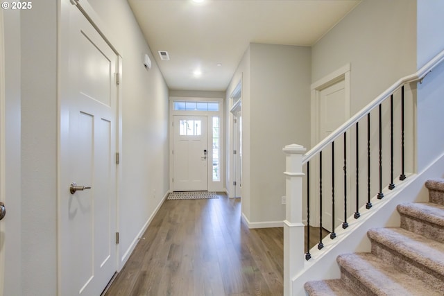 foyer entrance featuring baseboards, wood finished floors, and stairway