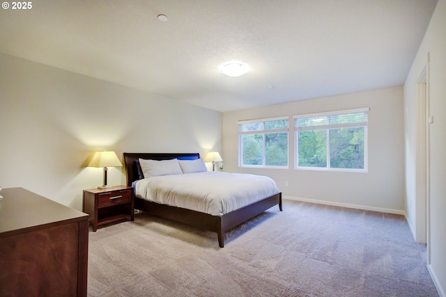 bedroom featuring light colored carpet and baseboards