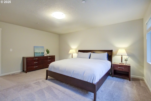 bedroom with baseboards, a textured ceiling, and light carpet