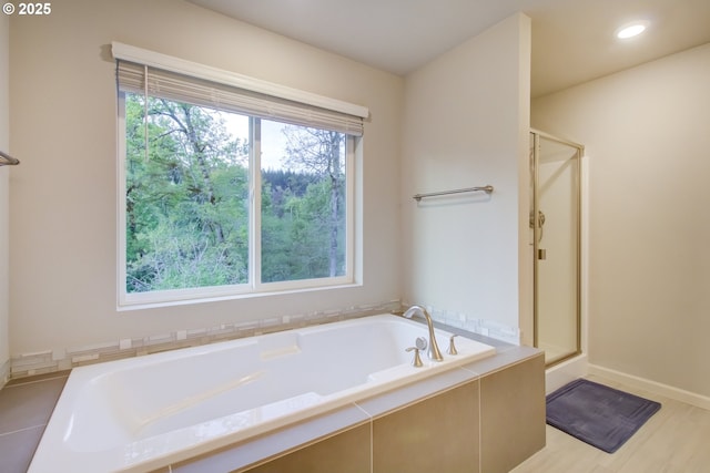 bathroom with baseboards, a bath, and a stall shower