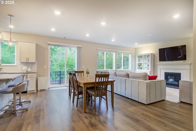 dining room featuring a glass covered fireplace, recessed lighting, and wood finished floors