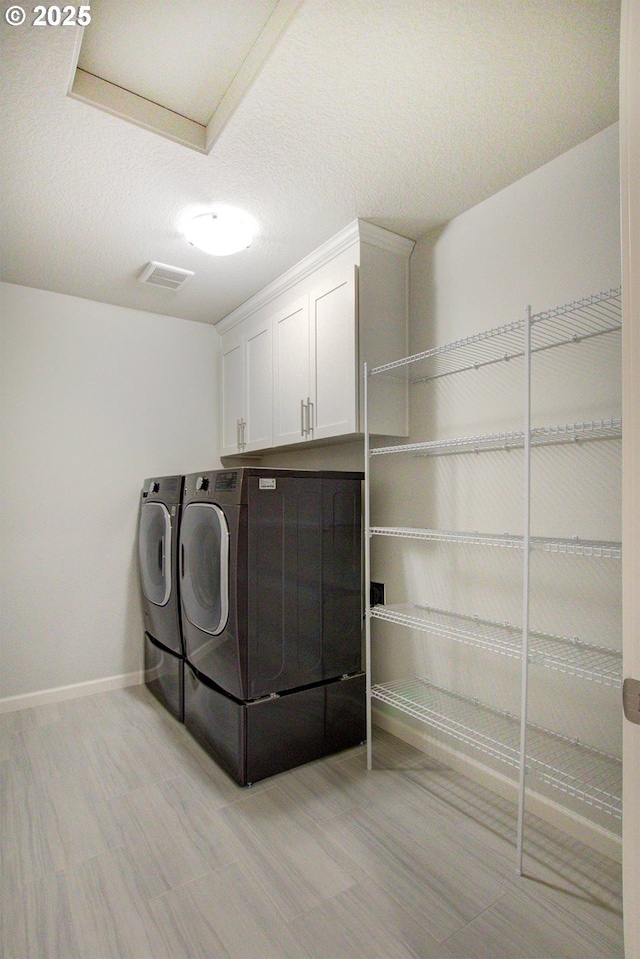 laundry room featuring separate washer and dryer, baseboards, light wood-style flooring, and cabinet space