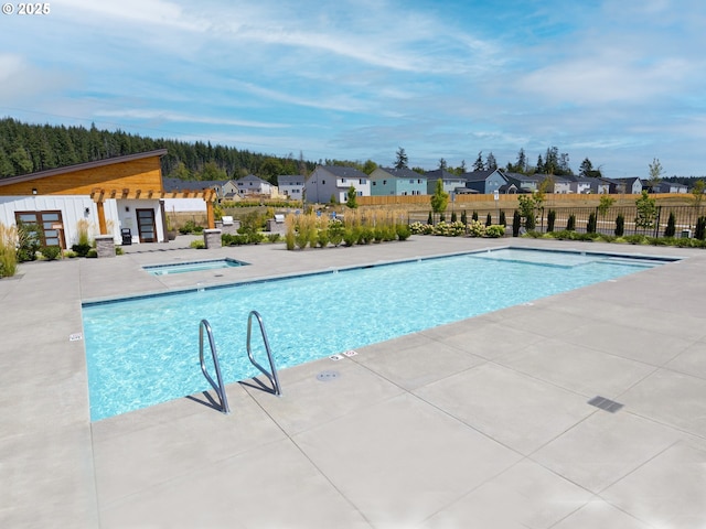 community pool with fence, a patio area, and a residential view