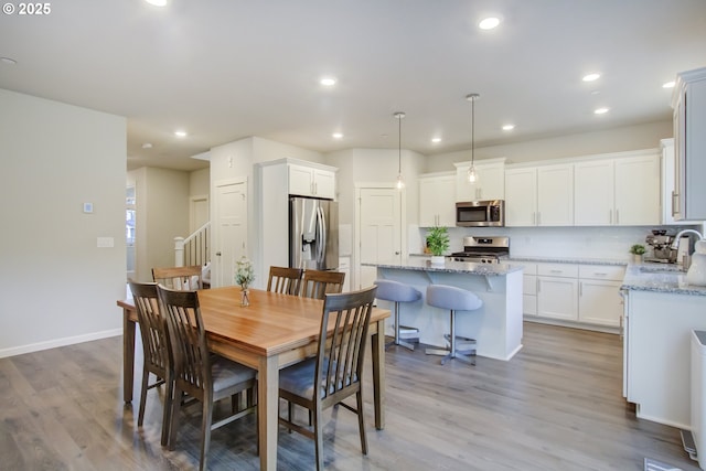dining area featuring recessed lighting, baseboards, wood finished floors, and stairway