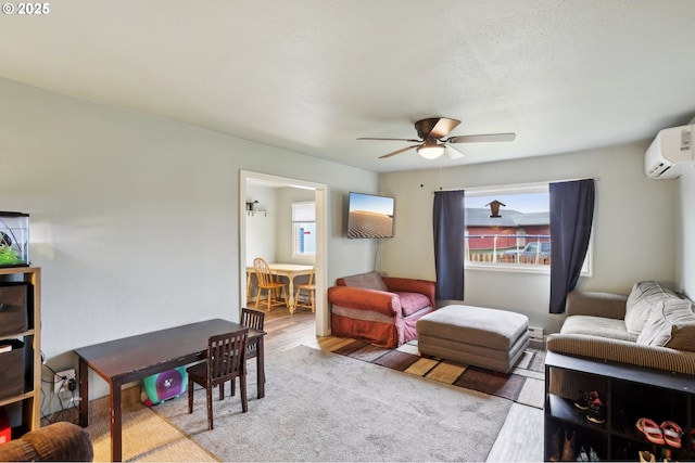 living room with a wall mounted air conditioner, ceiling fan, and light hardwood / wood-style flooring