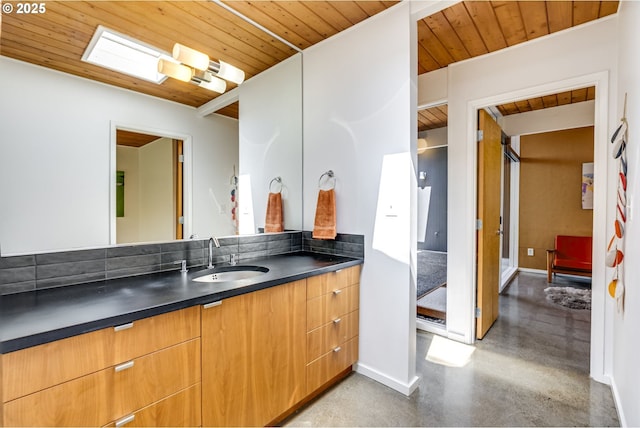 bathroom with vanity, wood ceiling, baseboards, and concrete floors