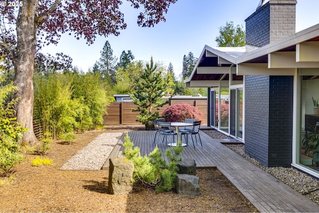 view of yard featuring a deck, fence, and outdoor dining area