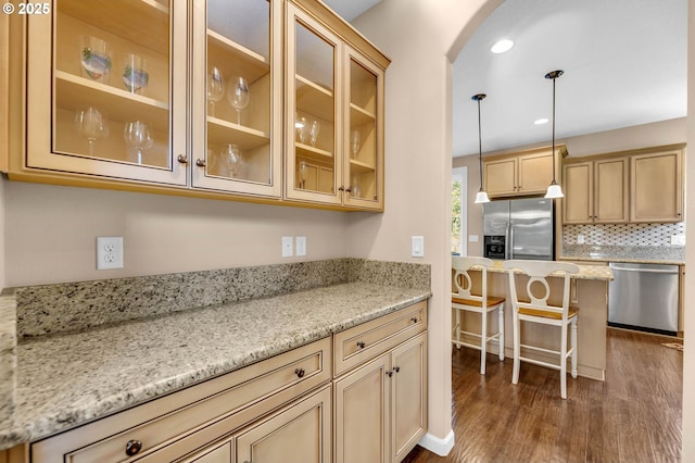 kitchen with stainless steel appliances, hanging light fixtures, tasteful backsplash, and light stone counters