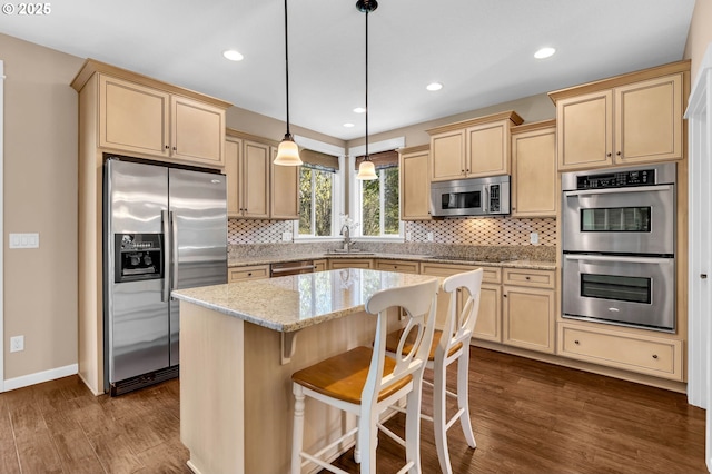 kitchen featuring sink, decorative light fixtures, light stone countertops, a center island, and stainless steel appliances