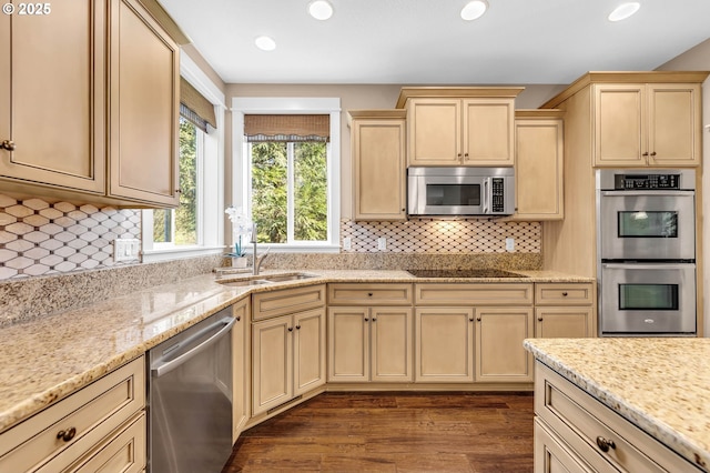 kitchen featuring light stone countertops, appliances with stainless steel finishes, sink, backsplash, and dark hardwood / wood-style floors