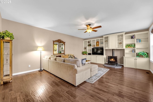 living room with a wood stove, ceiling fan, and dark hardwood / wood-style flooring