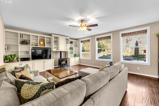 living room featuring a wood stove, ceiling fan, and dark hardwood / wood-style flooring