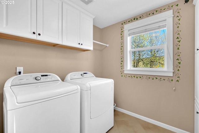 washroom featuring cabinets, washing machine and dryer, and light tile patterned flooring