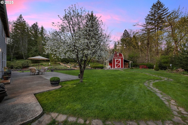 yard at dusk with a patio area and a storage unit