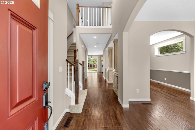 foyer entrance with a towering ceiling and dark hardwood / wood-style flooring