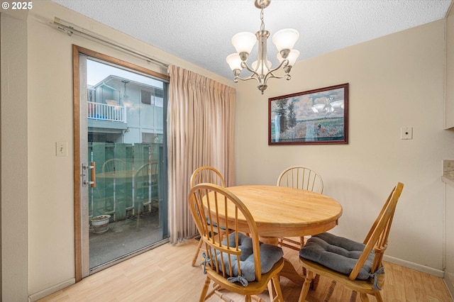 12841 SE Stark St Unit A19, Portland, OR 97233 - dining room featuring light wood-style floors, a chandelier, a textured ceiling, and baseboards