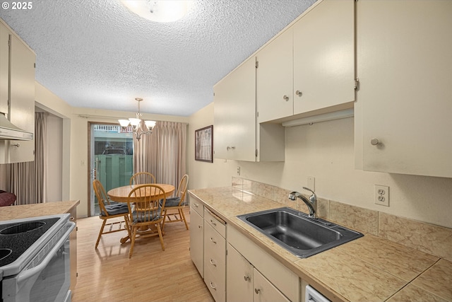 12841 SE Stark St Unit A19, Portland, OR 97233 - kitchen featuring a sink, a chandelier, light wood finished floors, a textured ceiling, and pendant lighting