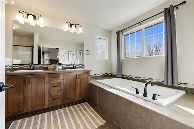 bathroom featuring vanity, a relaxing tiled tub, and tile patterned floors