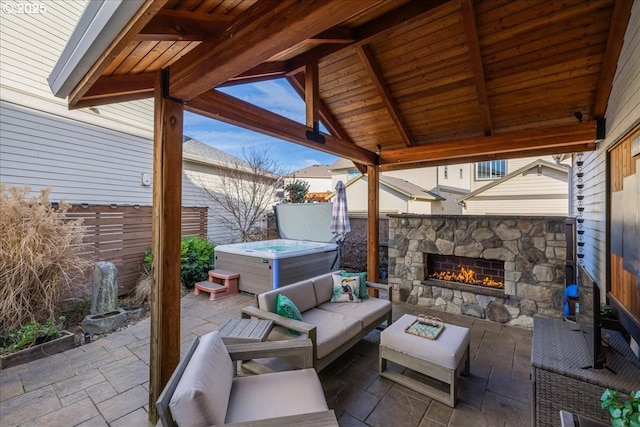 view of patio featuring a hot tub and an outdoor living space with a fireplace