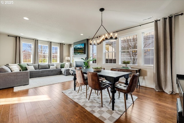 dining room featuring wood-type flooring, a fireplace, and a chandelier