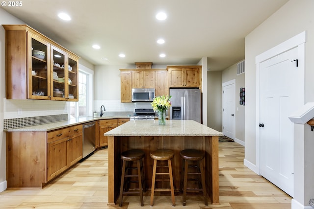 11862 White Ln, Oregon City, OR 97045 - kitchen featuring appliances with stainless steel finishes, a sink, light wood-style floors, a kitchen island, and decorative backsplash