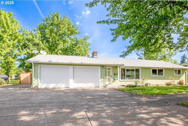 ranch-style house featuring driveway, a chimney, and an attached garage