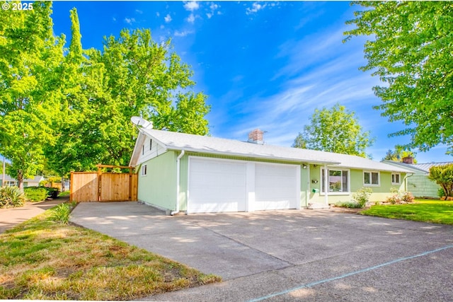 single story home featuring an attached garage, driveway, a chimney, and fence