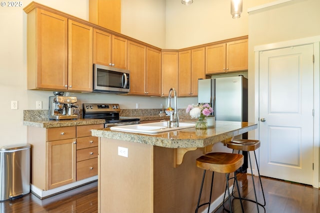 8996 SE Chloe Ln, Happy Valley, OR 97086 - kitchen featuring stainless steel appliances, dark wood finished floors, a sink, a kitchen island with sink, and a breakfast bar