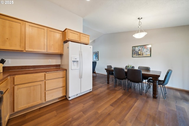kitchen with white refrigerator with ice dispenser, dark countertops, lofted ceiling, dark wood-type flooring, and hanging light fixtures