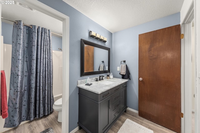14805 SW 109th Ave, Portland, OR 97224 - bathroom featuring wood finished floors, toilet, vanity, a textured ceiling, and baseboards