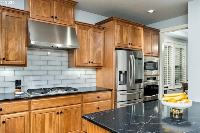 kitchen with under cabinet range hood, brown cabinets, and appliances with stainless steel finishes