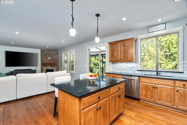 kitchen with light wood finished floors, dishwasher, tasteful backsplash, and a sink