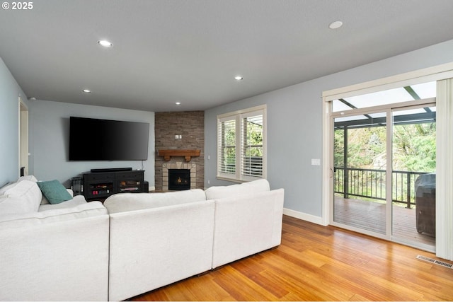 living area with visible vents, baseboards, light wood-style flooring, a fireplace, and recessed lighting