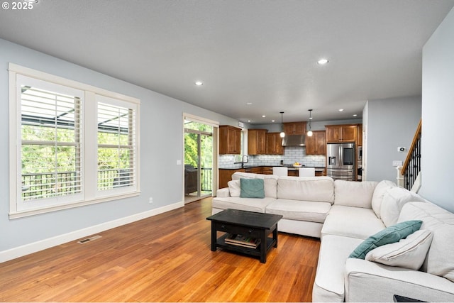 living room with visible vents, baseboards, stairway, recessed lighting, and light wood-style flooring