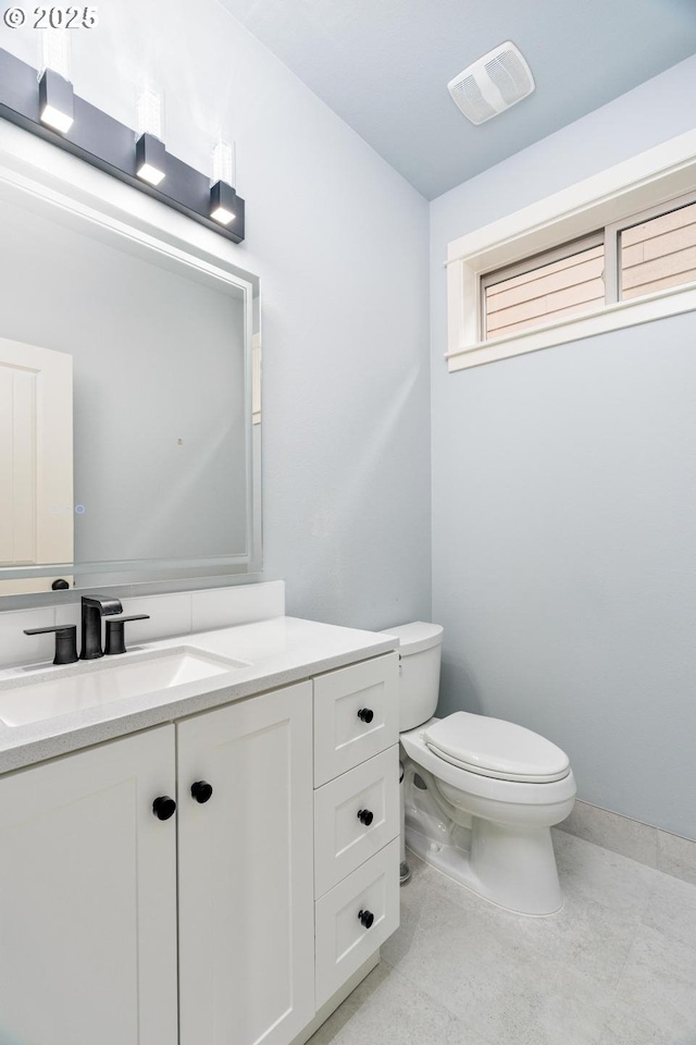 half bathroom with vanity, toilet, and visible vents