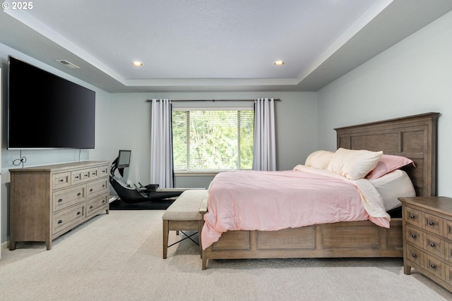 bedroom with recessed lighting, a tray ceiling, light carpet, and visible vents