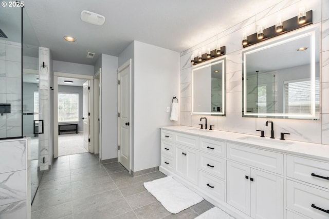 bathroom with double vanity, a shower with door, and a sink