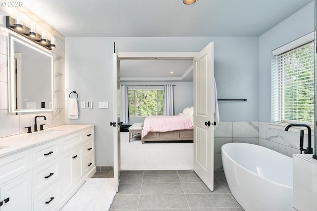 full bathroom with vanity, a freestanding bath, tile patterned flooring, ensuite bathroom, and tile walls