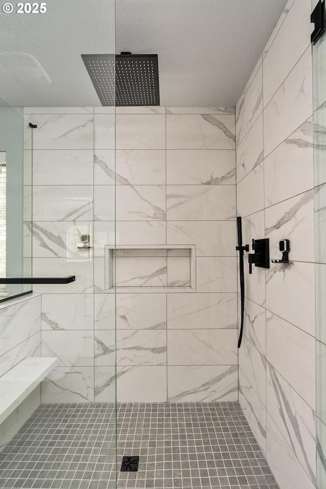 bathroom with a textured ceiling and tiled shower