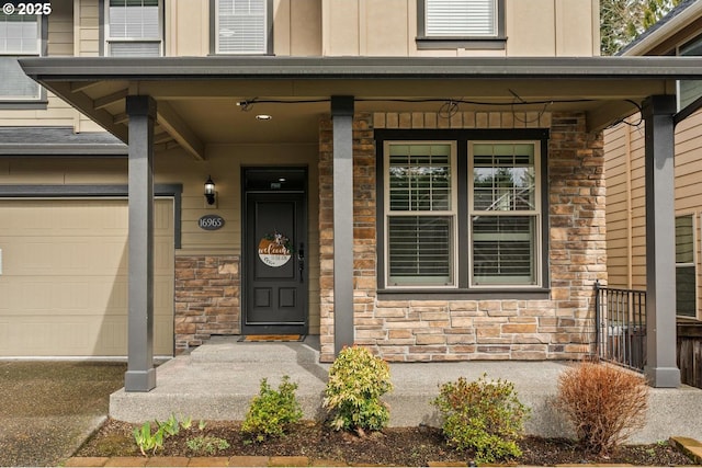 doorway to property with a porch, a garage, and stone siding