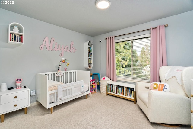 bedroom featuring baseboards, a nursery area, and carpet